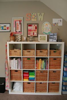 a book shelf filled with lots of books and wicker baskets next to a wall