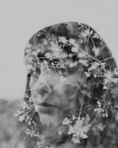 a black and white photo of a woman's face with flowers in her hair