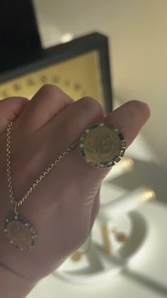 a hand holding a gold coin on a chain