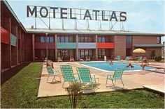 an old motel with a swimming pool and lawn chairs in front of the hotel's entrance