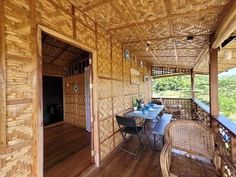 an outdoor dining area with wicker chairs and table on wooden deck overlooking the water