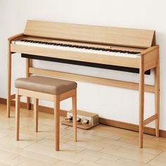 a wooden piano sitting in front of a white wall next to a bench and foot stool