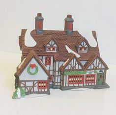 a small toy house with a wreath on the front and two story houses behind it