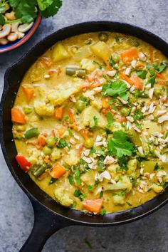 a pan filled with vegetables and rice on top of a table next to other dishes