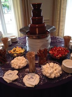 a table topped with plates and bowls filled with food next to a tall chocolate fountain