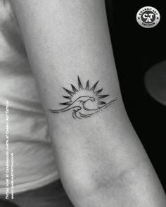 a woman's arm with a small sun tattoo on the left side of her arm