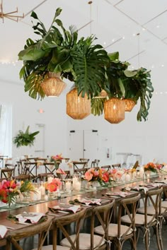 a long table is set with place settings and hanging planters for the centerpieces