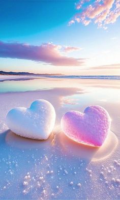 two heart shaped pillows sitting on top of a sandy beach