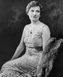 an old black and white photo of a woman in a dress with fur stole around her neck