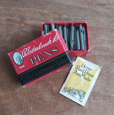 an old match box with some black matches in it next to a packet of erasers