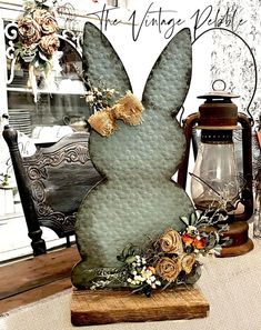 a metal bunny sitting on top of a wooden table next to a lamp and lantern