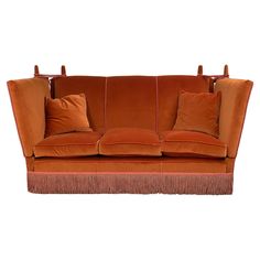 an orange velvet sofa with fringe trim and pillows