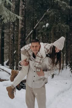 a man carrying a woman on his back in the snow