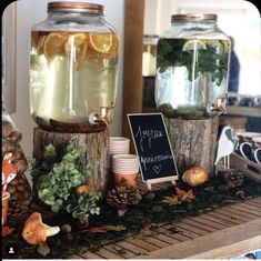 two jars filled with water and lemons on top of a wooden table next to other items