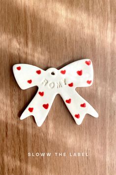 a white bow with red hearts on it and the word mom spelled in small letters