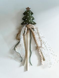 a small christmas tree made out of branches and ribbons on a white background with snowflakes