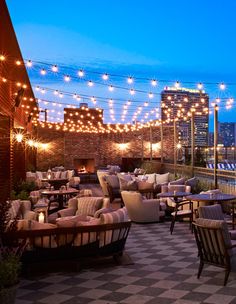 an outdoor seating area with lights strung over it