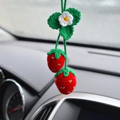 two crocheted strawberries hanging from a car dashboard