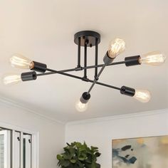 a black chandelier with six lights hanging from it's ceiling in a living room