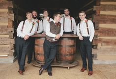 a group of men standing next to each other in front of wooden barrels with flowers on them