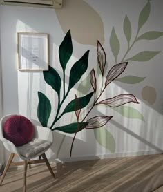 a chair sitting in front of a wall with leaves painted on it