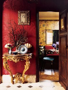 a room with red walls and a table in the middle, decorated with flowers on it