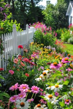 a white picket fence surrounded by colorful flowers