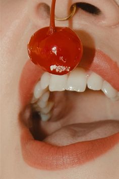 a close up of a person's mouth with a cherry attached to it