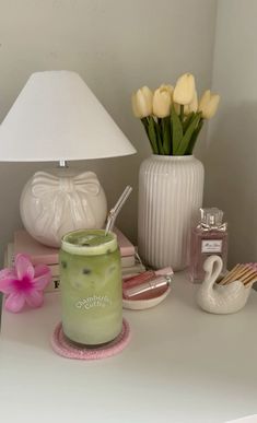 a white table topped with a lamp and vase filled with flowers