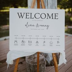 a welcome sign on a wooden easel for an outdoor wedding ceremony in the woods