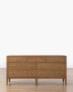 a wooden dresser sitting on top of a hard wood floor next to a white wall