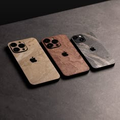 three wooden iphone cases sitting next to each other on top of a black countertop