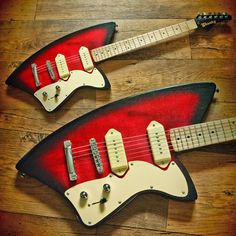 two red and black electric guitars sitting on top of a wooden floor next to each other