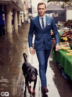 a man in a suit walking his dog down the street