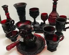 a table topped with lots of red glass vases and cups next to each other