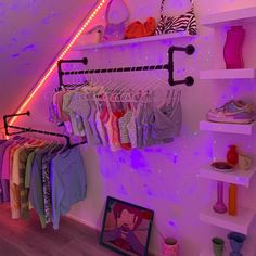 there is a closet with clothes and shoes on the shelves in front of it that are lit up by purple lights