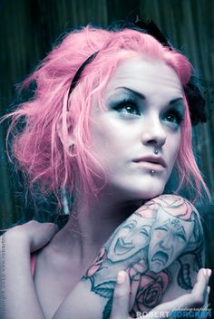 a woman with pink hair and tattoos on her arm