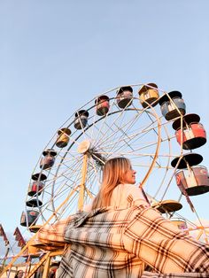 a woman is sitting in front of a ferris wheel