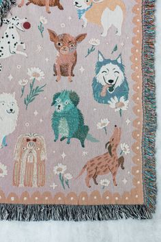 a blanket with dogs on it and fringes around the edges is laying on a white surface