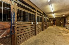 the inside of a stable with wooden stalls and bars on each side, lined up against the wall