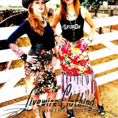 two women standing next to each other in front of a fence