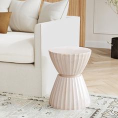 a white couch sitting next to a wooden table on top of a carpeted floor