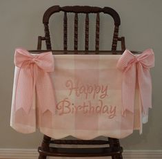 a chair with a happy birthday sign on it's back and pink bows around the seat