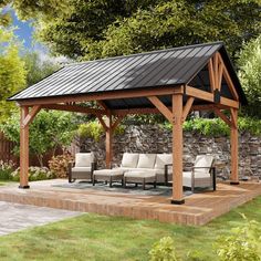 a wooden gazebo with chairs under it in the grass next to a stone wall