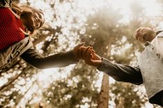 two people holding hands in front of trees