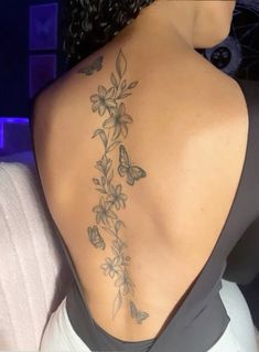 the back of a woman's shoulder with flowers and butterflies on her left side