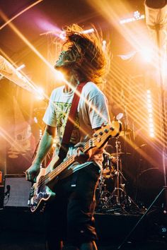 a man with long hair playing guitar on stage