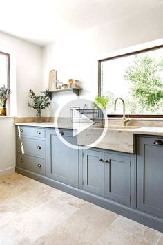 a large kitchen with blue cabinets and marble counter tops in front of an open window