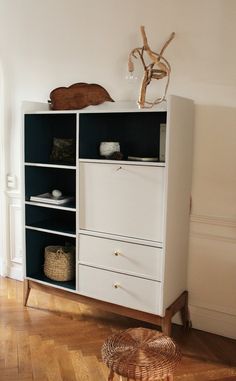 a white bookcase with drawers and baskets on top