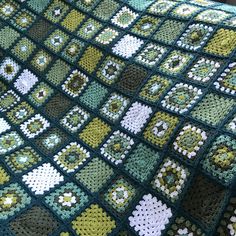 a crocheted blanket with squares and flowers on it